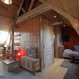 Chalet en bois à Basse-Normandie, intérieur chaleureux avec poutres apparentes.