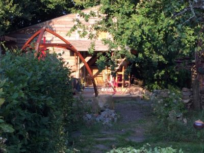 Cabane en bois à Basse-Normandie, entourée de verdure et avec une terrasse accueillante.