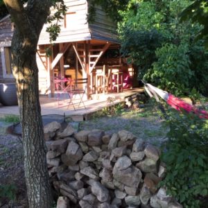 Cabane en bois à Basse-Normandie, avec terrasse et hamac sous les arbres.