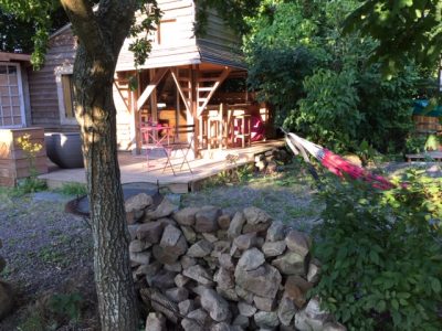 Cabane en bois à Basse-Normandie, avec terrasse et hamac sous les arbres.