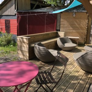 Hébergement insolite en Basse-Normandie avec terrasse en bois et fauteuils confortables.