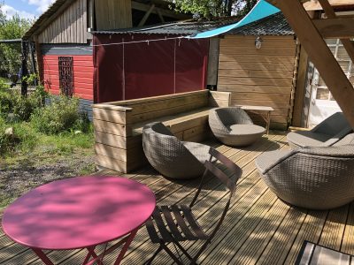 Hébergement insolite en Basse-Normandie avec terrasse en bois et fauteuils confortables.
