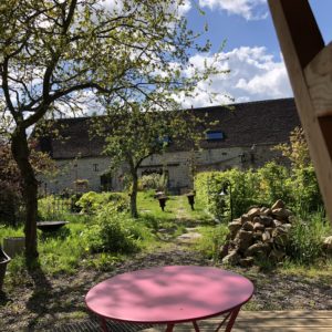 Hébergement insolite en cabane, avec un jardin verdoyant et une table rose.