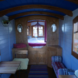 Charmant hébergement insolite en roulotte, intérieur en bois avec un lit douillet.