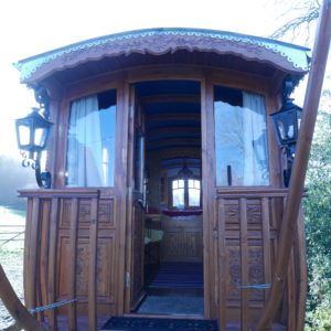 Charmante roulotte en bois, ornée de lanternes, offrant un séjour unique en Basse-Normandie.