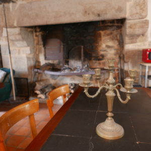 Hébergement insolite en Basse-Normandie avec une cheminée en pierre et un chandelier vintage.