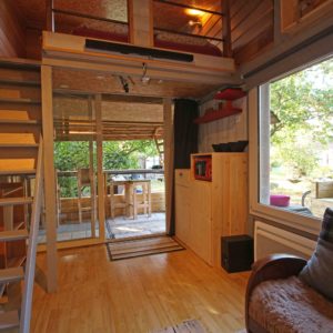 Cabane en bois avec mezzanine, lumineuse et entourée de verdure en Basse-Normandie.