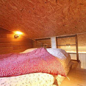 Chambre en mezzanine cosy avec un lit douillet et un plafond en bois chaleureux.
