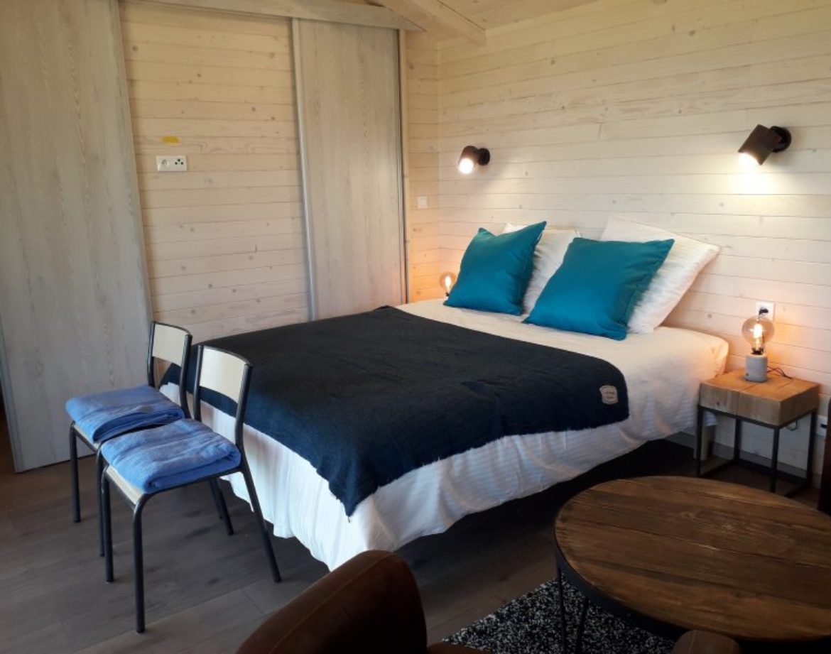 Chalet moderne en bois avec lit douillet et décoration chaleureuse à Languedoc-Roussillon.