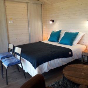 Chalet moderne en bois avec lit douillet et décoration chaleureuse à Languedoc-Roussillon.