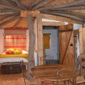 Cabane en bois avec un lit douillet et des éléments naturels, au cœur du Languedoc-Roussillon.