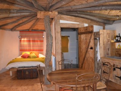 Cabane en bois avec un lit douillet et des éléments naturels, au cœur du Languedoc-Roussillon.