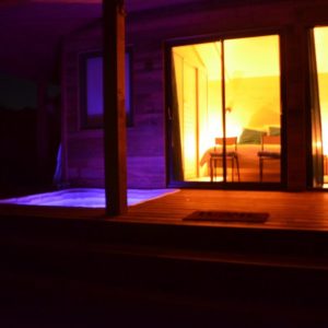 Cabane insolite avec jacuzzi, éclairage chaleureux et ambiance nocturne apaisante.