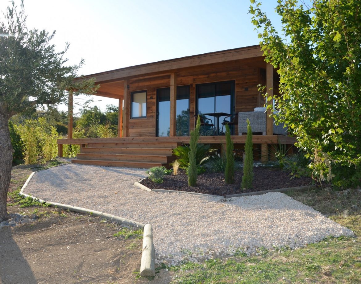 Chalet en bois avec terrasse, entouré de verdure à Languedoc-Roussillon.