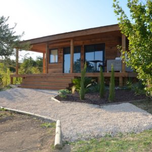 Chalet en bois avec terrasse, entouré de verdure à Languedoc-Roussillon.