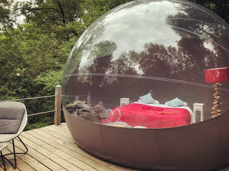 Bulle transparente en pleine nature, lit douillet et ambiance romantique.