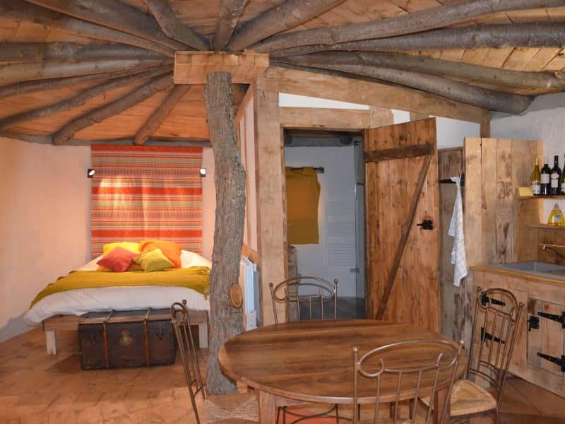 Chalet en bois avec un lit douillet et des poutres apparentes au plafond.
