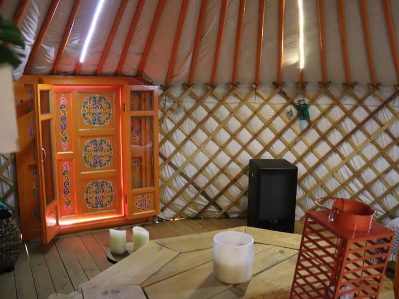 Intérieur dune yourte colorée avec une porte ornée et un coin salon chaleureux.