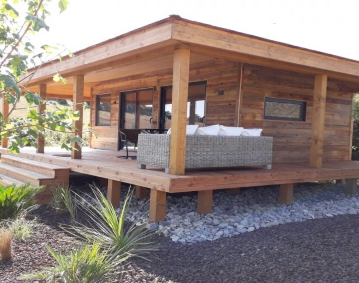Cabane en bois avec terrasse, entourée de plantes exotiques à Languedoc-Roussillon.