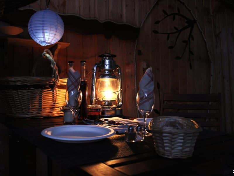 Cabane romantique avec une table éclairée par une lanterne et des décorations chaleureuses.