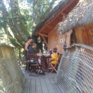 Cabane dans les arbres en Auvergne-Rhône-Alpes, avec terrasse en bois et famille réunie.