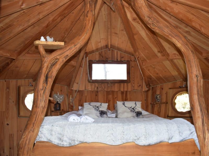 Cabane en bois en Bretagne, avec un lit douillet et des détails en rondins.