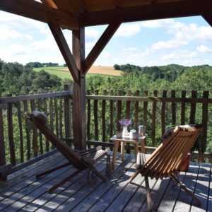 Cabane perchée en Bretagne avec terrasse en bois et vue sur la nature verdoyante.
