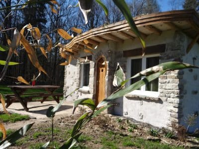 Hébergement insolite en pierre avec toit en bois, entouré de verdure à Grand-Est.