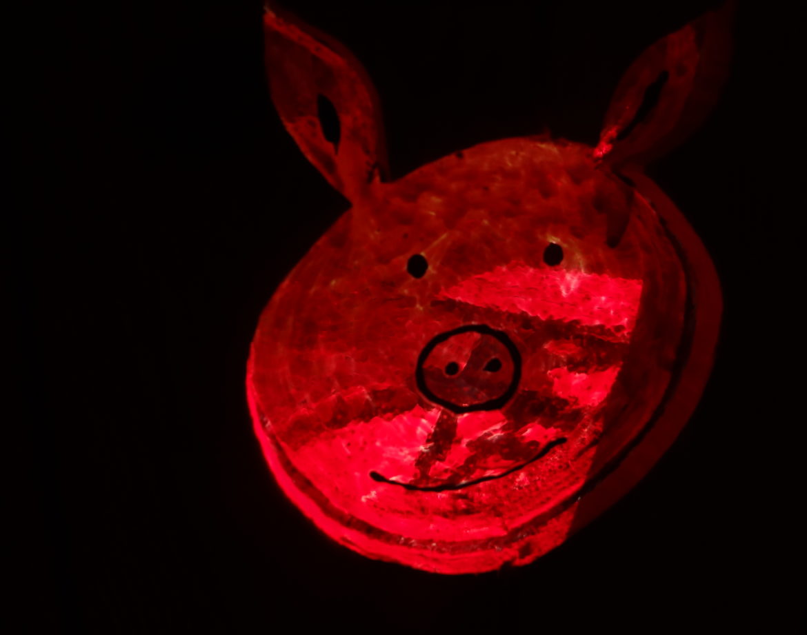 Hébergement insolite en forme de cochon, illuminé dune douce lumière rouge.