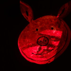 Hébergement insolite en forme de cochon, illuminé dune douce lumière rouge.