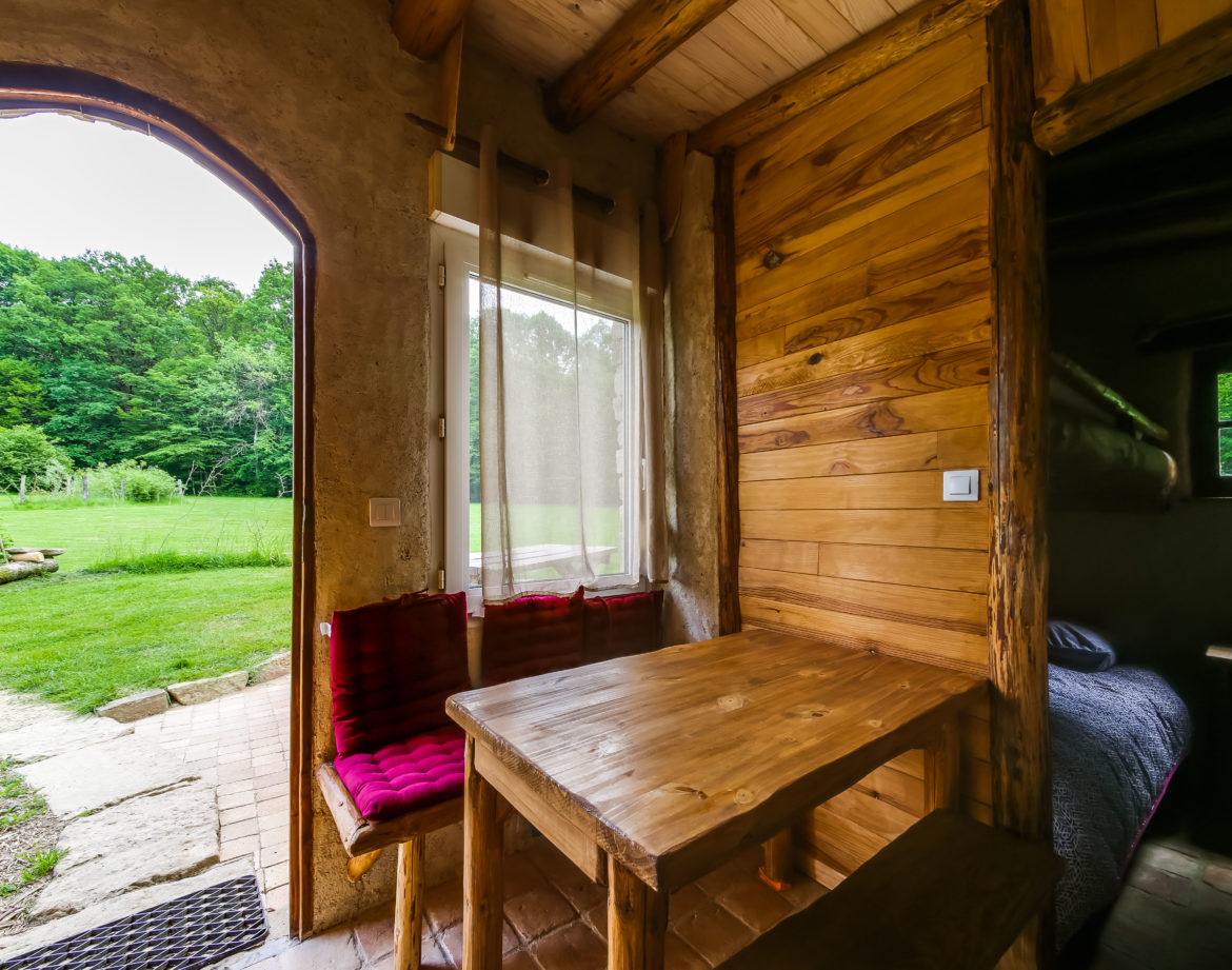 Hébergement insolite en bois avec vue sur la nature, table en bois et ambiance chaleureuse.