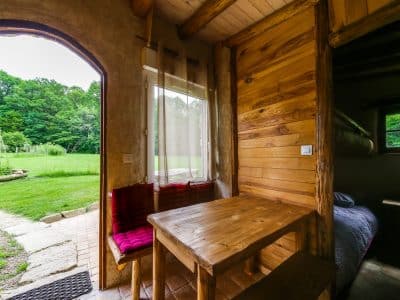 Hébergement insolite en bois avec vue sur la nature, table en bois et ambiance chaleureuse.