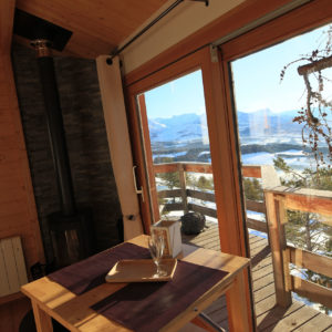 Cabane en bois avec vue panoramique sur les montagnes et un coin repas cosy.