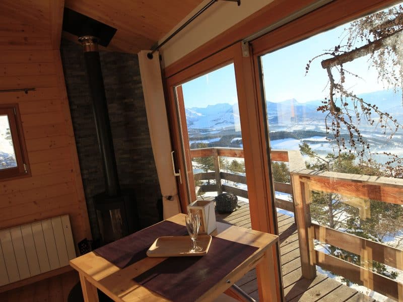 Cabane en bois avec vue panoramique sur les montagnes et un coin repas cosy.