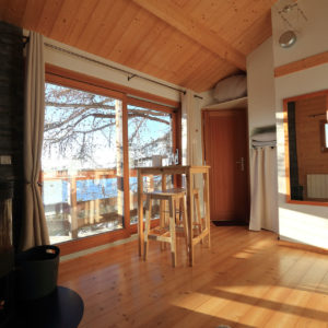 Cabane en bois lumineuse avec vue sur le lac et poêle à bois chaleureux.
