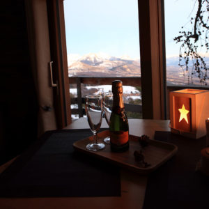 Cabane en bois avec vue sur les montagnes, champagne et bougies créent une ambiance romantique.