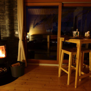 Hébergement insolite en bois avec poêle à bois, vue nocturne sur la vallée.
