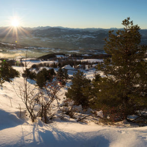 Cabane en bois perchée, vue panoramique sur les montagnes enneigées au coucher du soleil.