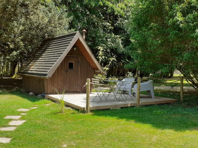 Charmant chalet en bois avec terrasse, entouré de verdure paisible.