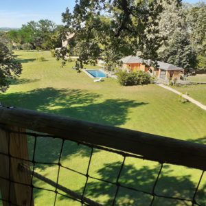 Cabane perchée en Bourgogne, vue sur un grand jardin et une piscine.
