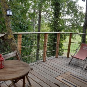 Cabane perchée en Bourgogne avec terrasse en bois et lanternes décoratives.
