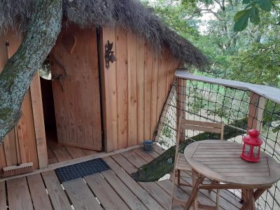 Cabane perchée en bois avec terrasse, lanternes et vue sur la nature en Bourgogne.