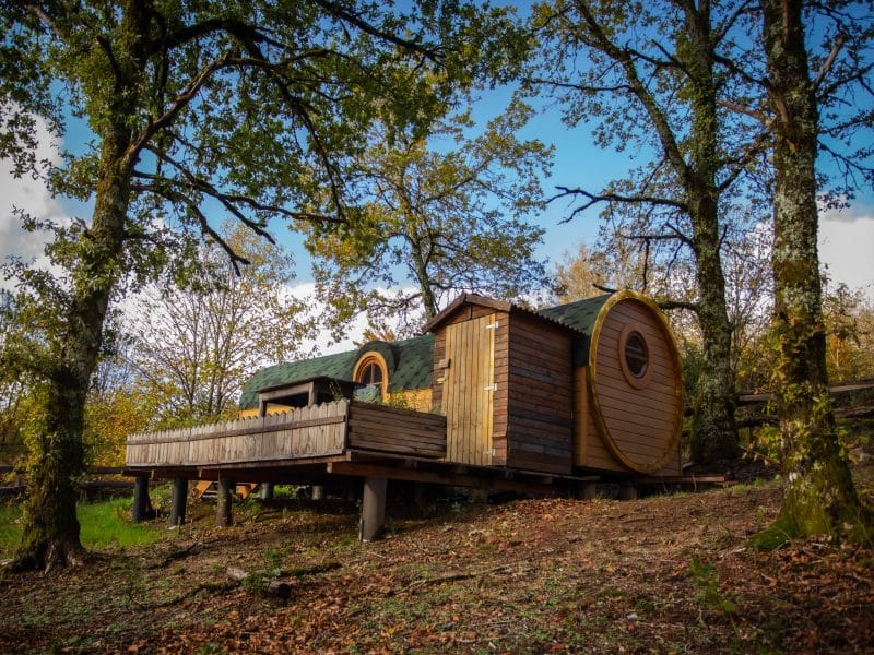 Hébergement insolite en forme de cabane ronde, entouré darbres verdoyants.