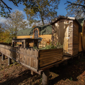 Hébergement insolite en forme de roulotte, entouré de verdure et dun espace extérieur.