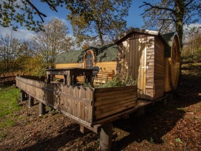 Hébergement insolite en forme de roulotte, entouré de verdure et dun espace extérieur.
