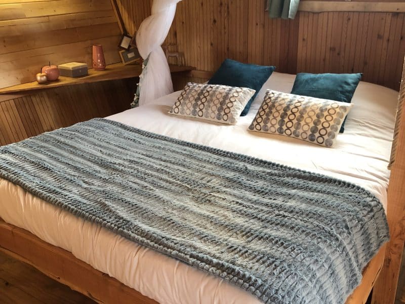 Chambre en bois cosy avec lit double, draps doux et décoration chaleureuse.