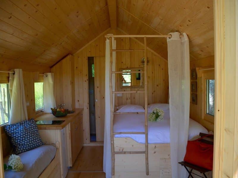 Cabane en bois chaleureuse avec lit douillet et échelle en bois.