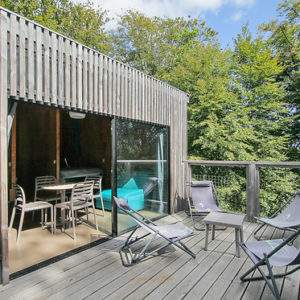 Cabane moderne en bois avec terrasse, entourée de verdure à Basse-Normandie.