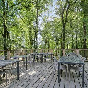 Hébergement insolite en cabane dans les arbres, terrasse en bois entourée de verdure.