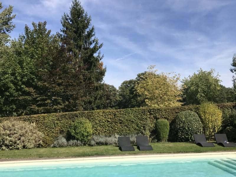 Hébergement touristique avec piscine, entouré de verdure et chaises longues confortables.